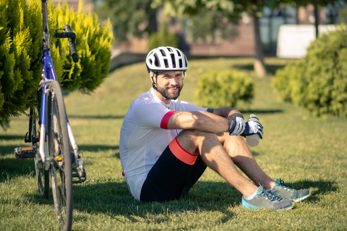 Man with bottle of water sitting on grass