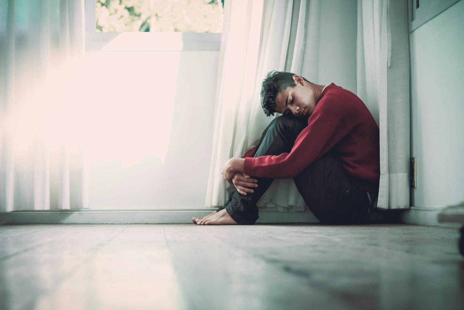 man beside white frame window suffering from Bi-Polar Disorder